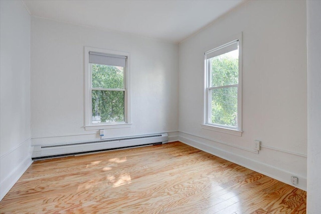 spare room featuring baseboard heating and wood finished floors