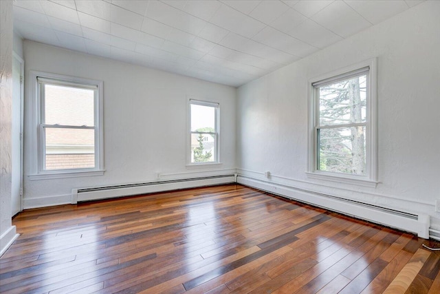 spare room featuring wood-type flooring and a baseboard heating unit