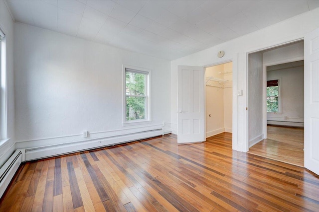 unfurnished bedroom with a baseboard heating unit, a baseboard radiator, and hardwood / wood-style floors