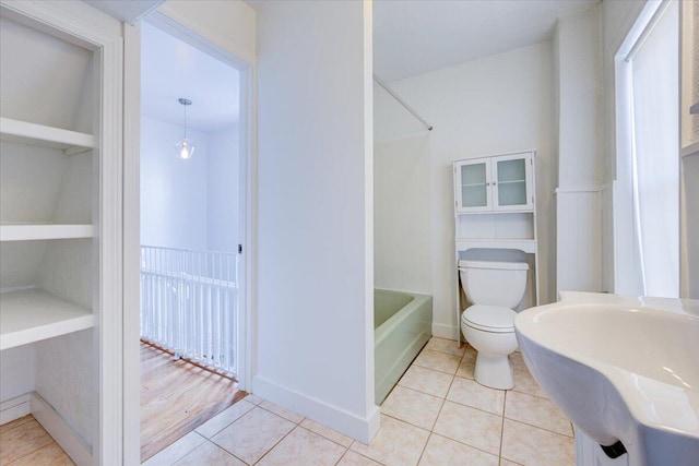 full bath featuring toilet, tile patterned flooring, baseboards, and a sink