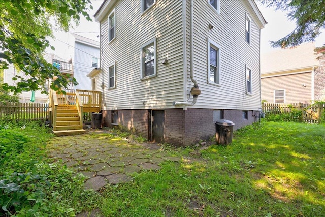 view of property exterior with a deck, a yard, a patio area, and fence