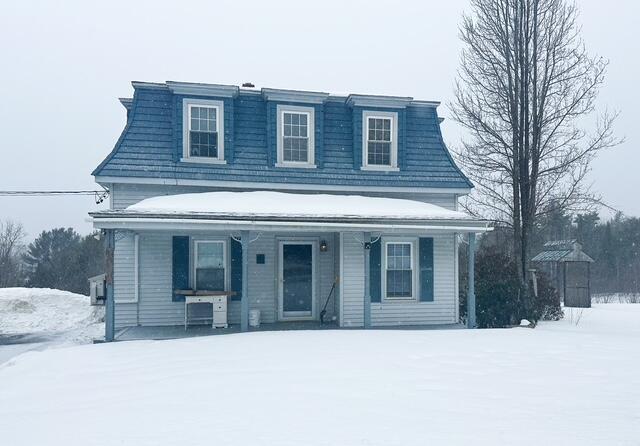 second empire-style home featuring mansard roof and a porch