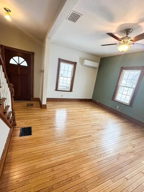 entryway featuring light wood-type flooring, a healthy amount of sunlight, visible vents, and a wall mounted air conditioner