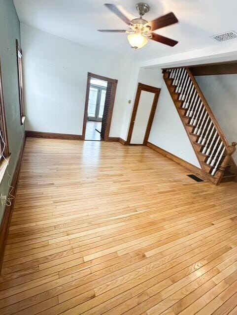 unfurnished living room with stairway, light wood-style flooring, visible vents, and baseboards