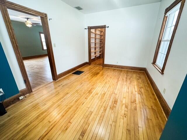 spare room featuring light wood-style flooring, visible vents, and baseboards