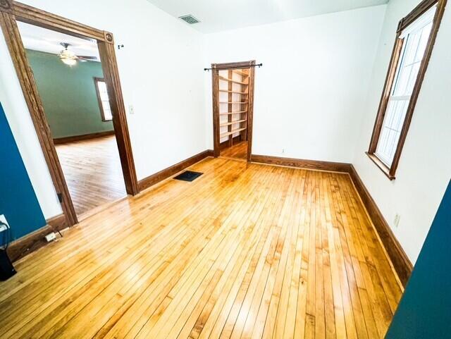 empty room featuring baseboards, visible vents, and light wood finished floors