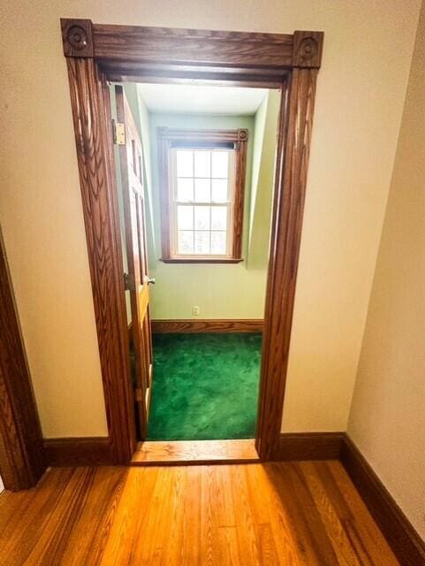 hallway featuring wood finished floors and baseboards