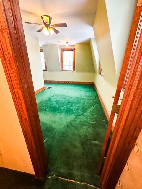 additional living space featuring carpet, baseboards, and a ceiling fan