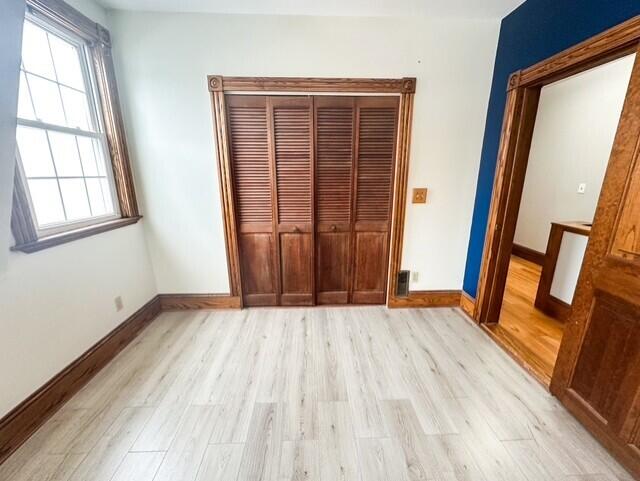 unfurnished bedroom featuring light wood-type flooring and baseboards