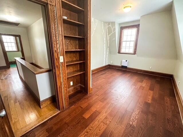 interior space featuring dark wood-style flooring, multiple windows, and baseboards