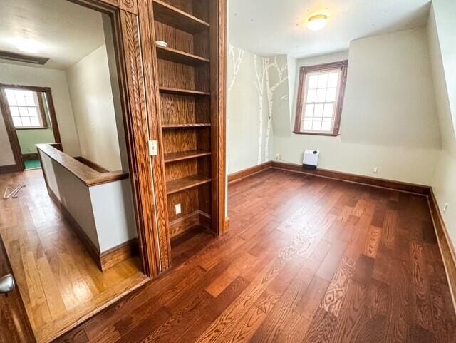 interior space featuring dark wood-style flooring, multiple windows, and baseboards