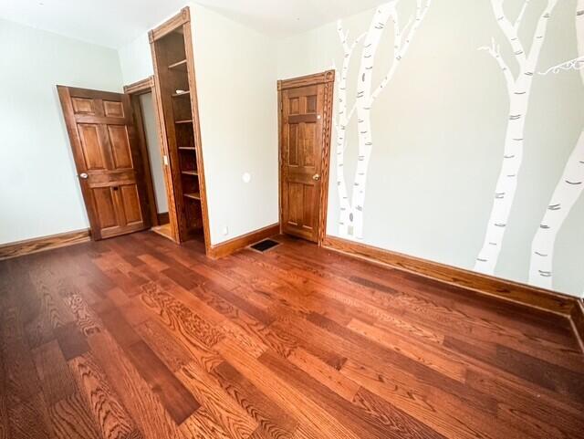 interior space with wood finished floors, visible vents, and baseboards