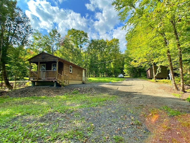 view of yard featuring a porch and gravel driveway