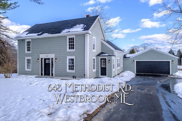 view of front of home with a detached garage, a chimney, and an outdoor structure