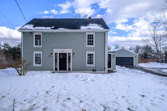 snow covered house with a detached garage and an outdoor structure