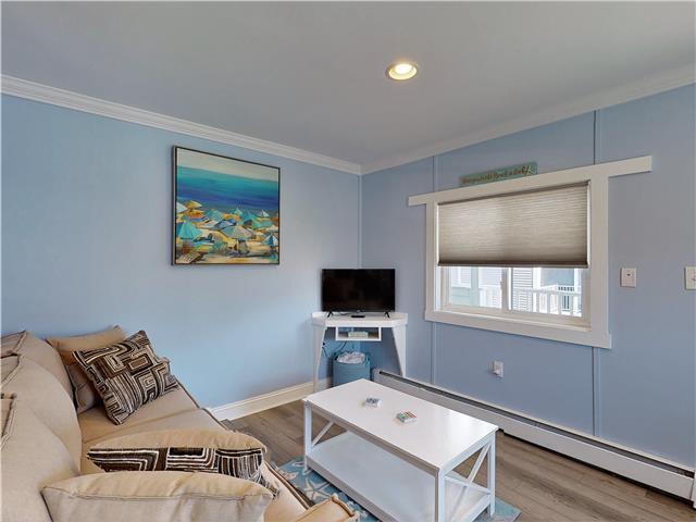 living area featuring recessed lighting, wood finished floors, baseboards, baseboard heating, and crown molding