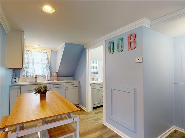 kitchen featuring light wood-style floors, white dishwasher, light countertops, and a sink