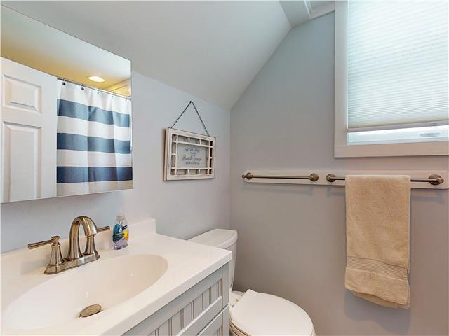 bathroom with toilet, a shower with curtain, vanity, and lofted ceiling