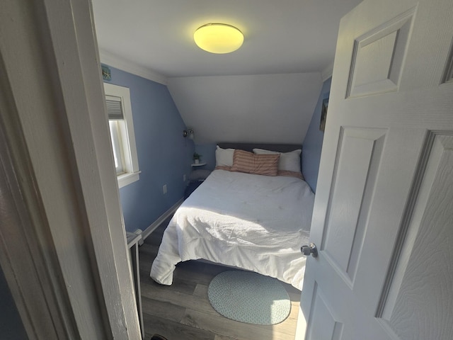 bedroom featuring lofted ceiling, baseboards, and wood finished floors