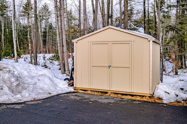 snow covered structure with an outdoor structure and a shed