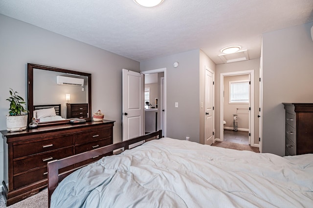 bedroom with a textured ceiling, a wall mounted AC, and attic access