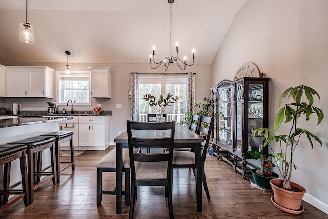 dining space with lofted ceiling, dark wood-style flooring, a notable chandelier, and baseboards