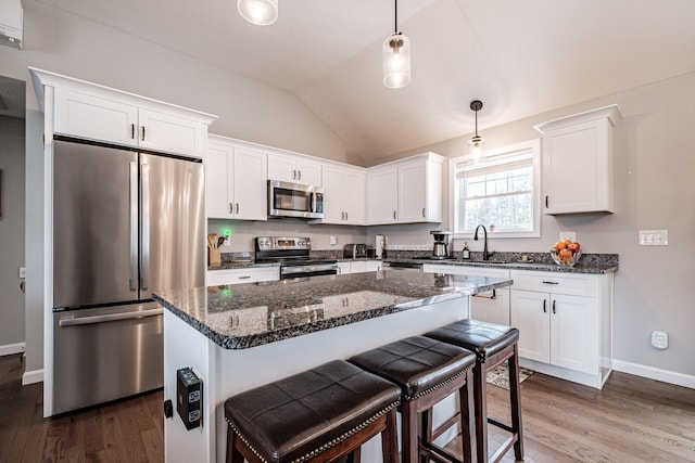 kitchen with vaulted ceiling, stainless steel appliances, dark wood-type flooring, and white cabinets