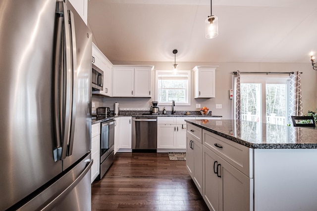 kitchen with white cabinets, dark wood-style floors, decorative light fixtures, stainless steel appliances, and a sink