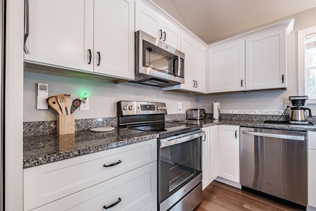 kitchen featuring dark stone countertops, white cabinetry, appliances with stainless steel finishes, and dark wood-type flooring