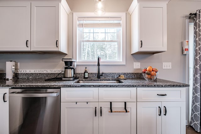 kitchen with dark stone counters, white cabinetry, dishwasher, and a sink