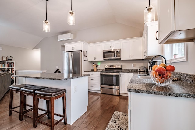 kitchen with white cabinets, lofted ceiling, dark wood-style floors, appliances with stainless steel finishes, and a center island