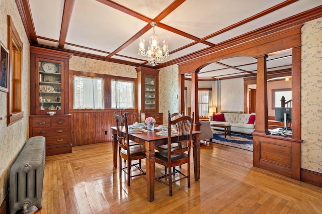 dining room with radiator, coffered ceiling, decorative columns, wallpapered walls, and light wood-style flooring