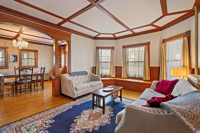 living room with a wainscoted wall, wood finished floors, coffered ceiling, and a notable chandelier