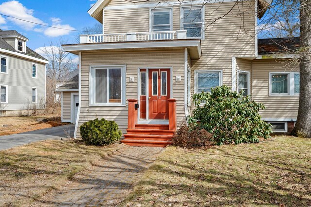 view of front of home featuring a balcony, driveway, a front lawn, and entry steps