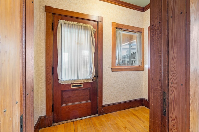 doorway with baseboards, wallpapered walls, ornamental molding, and hardwood / wood-style flooring