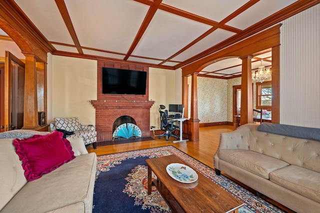 living area featuring coffered ceiling, wallpapered walls, wood finished floors, and ornate columns