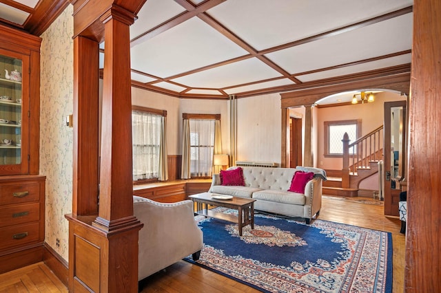 living area with decorative columns, wallpapered walls, coffered ceiling, and stairway