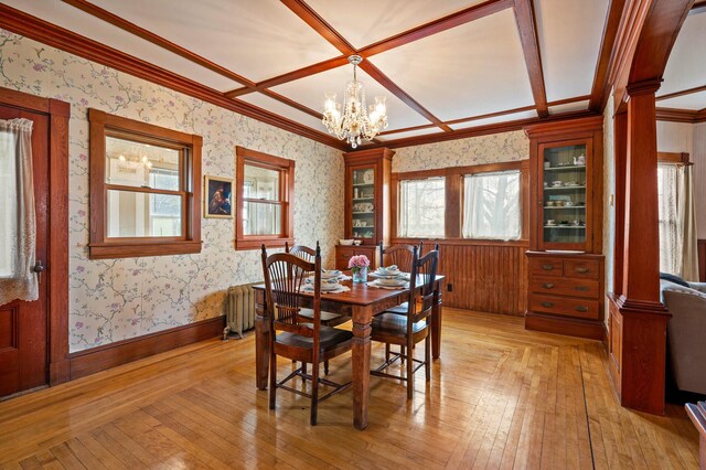 dining space with coffered ceiling, wallpapered walls, a chandelier, and light wood-style floors