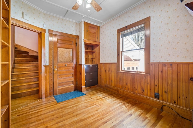 empty room with wallpapered walls, a wainscoted wall, and ceiling fan