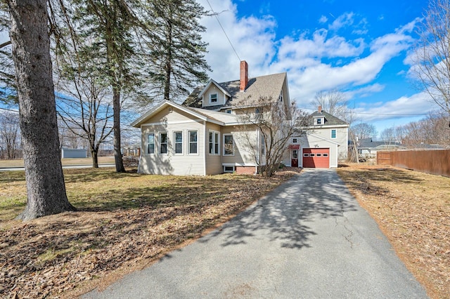 view of front of property with aphalt driveway, fence, and a chimney