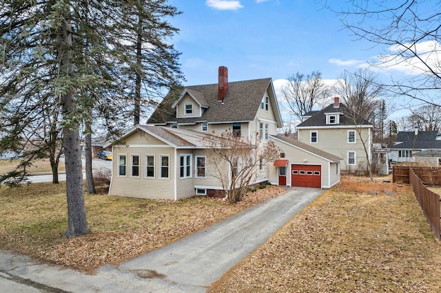 view of front of property featuring a chimney, fence, an attached garage, an outdoor structure, and aphalt driveway