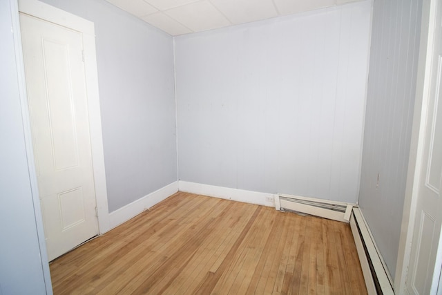 unfurnished room featuring a baseboard heating unit and light wood finished floors