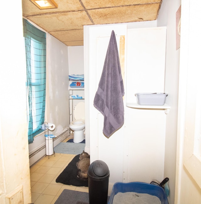 bathroom with a baseboard heating unit, a paneled ceiling, toilet, and tile patterned floors