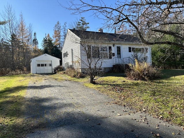 view of front facade featuring a garage, aphalt driveway, a front lawn, and an outdoor structure