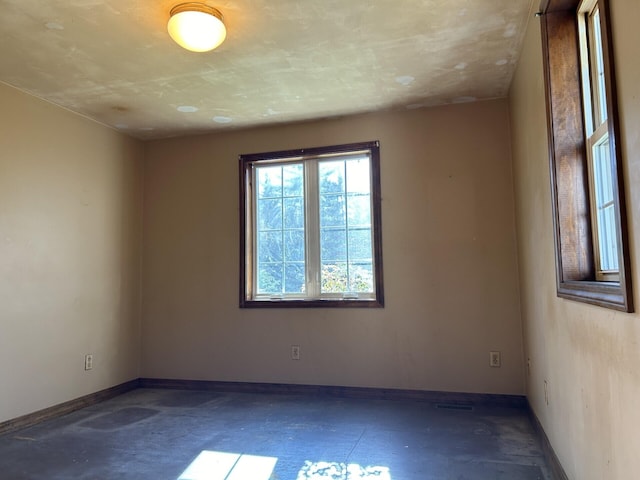 empty room featuring concrete floors and baseboards