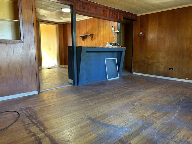 unfurnished room with dark wood-type flooring, crown molding, wooden walls, and baseboards