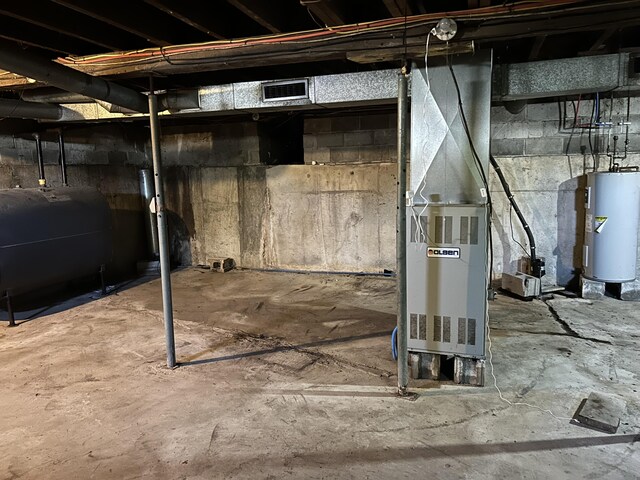 unfinished below grade area featuring heating unit, heating fuel, water heater, and visible vents