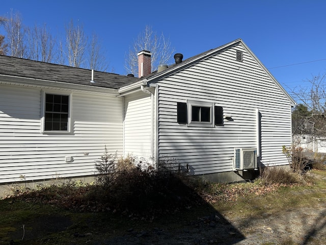 view of side of property featuring a chimney and central AC unit