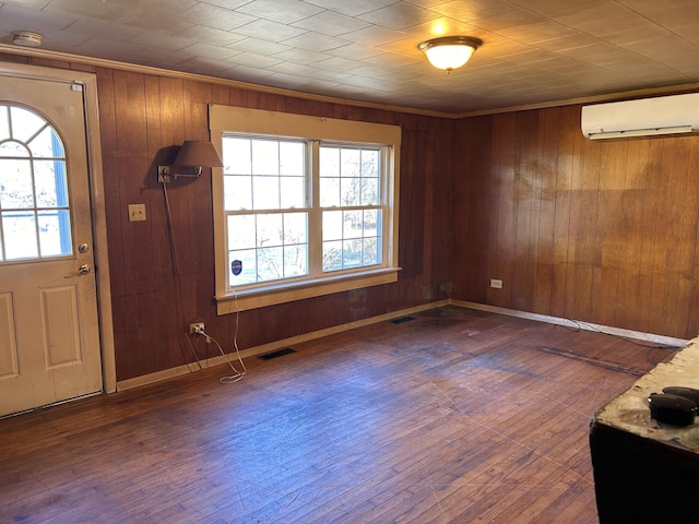 foyer with a wall unit AC, wood-type flooring, visible vents, and crown molding