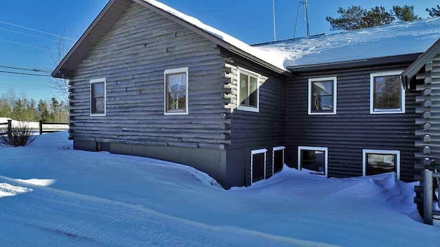 view of snowy exterior featuring log siding